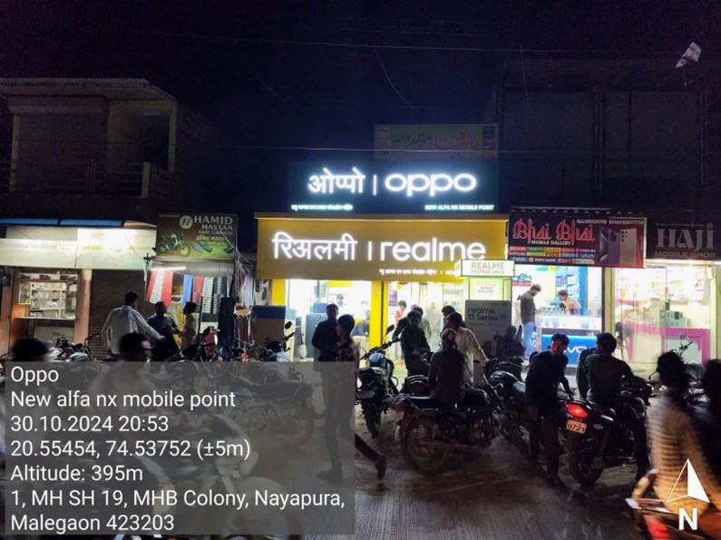 After — OPPO backlit signage installed above the realme board at night, New Alfa NX Mobile Point, Malegaon